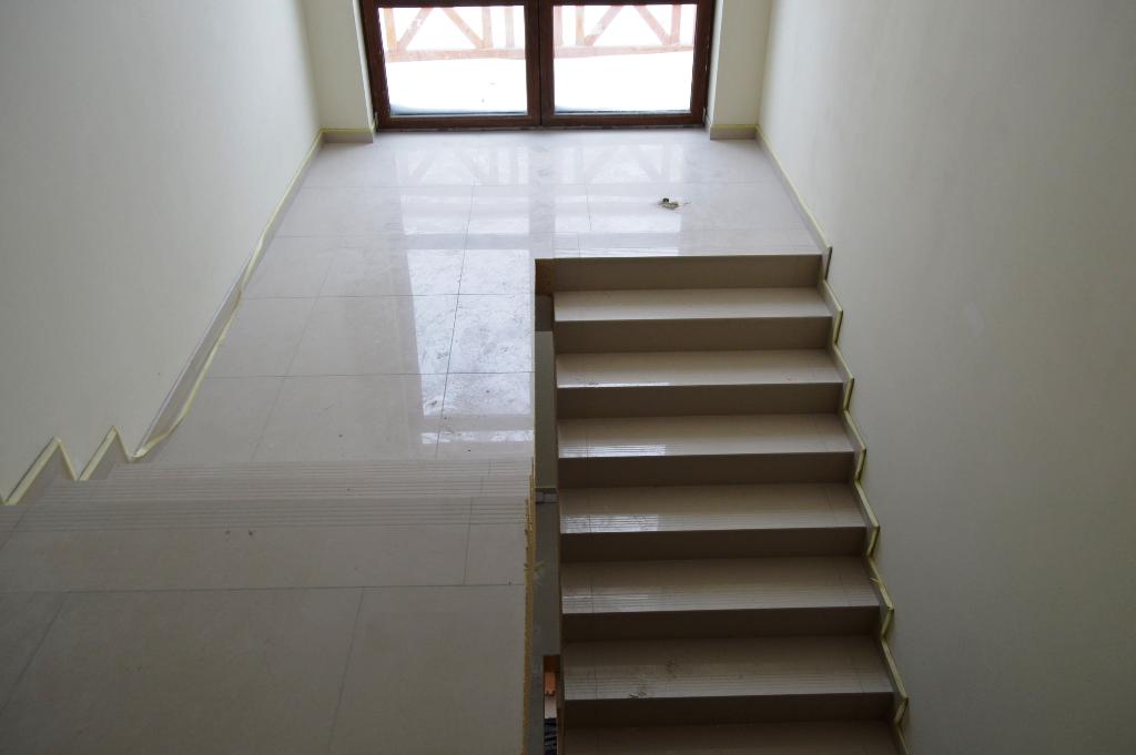 Układanie gresu wielkoformatowego na schodach i podłodze korytarza | Glazurmistrz.pl